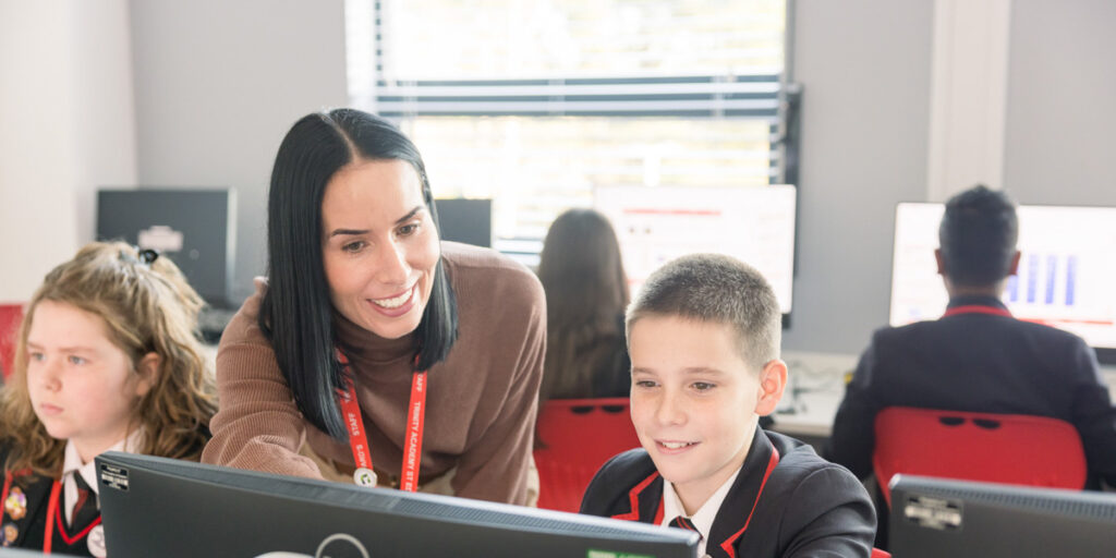 Trinity Academy St Edward's teacher helping students on computers